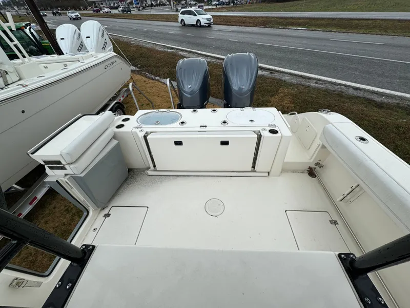 Slide: The Image of 2021 Cobia 301 CC boat interior with dual engines, parked near a road. - 16