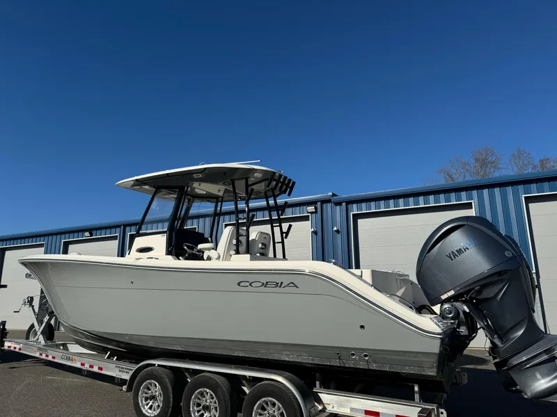Slide: The Image of 2021 Cobia 301 CC boat on trailer, parked outside blue storage units. - 3