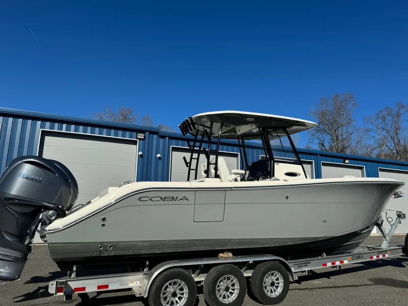 Slide: The Image of 2021 Cobia 301 CC boat on trailer, parked outside blue building. - 6