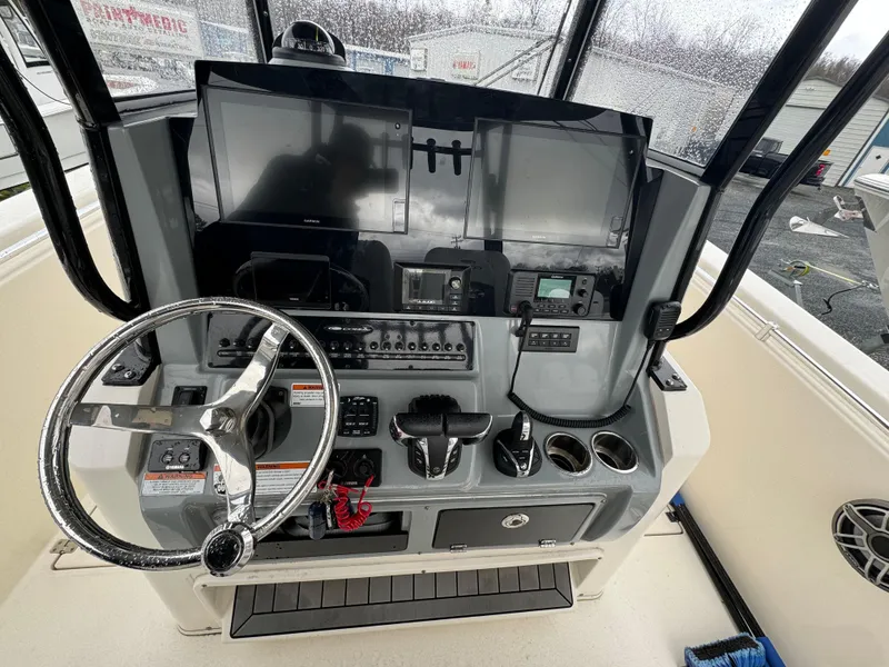 Slide: The Image of 2021 Cobia 301 CC boat dashboard with steering wheel and electronic controls. - 8