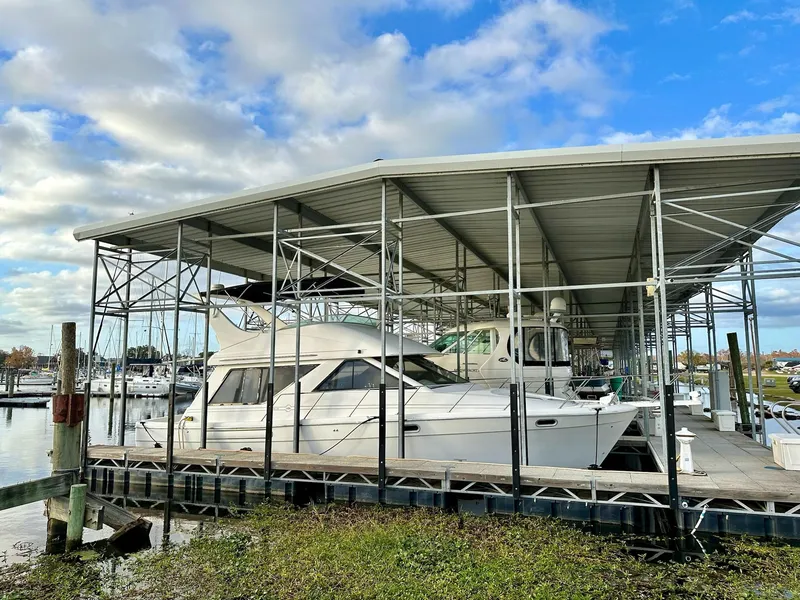 The Image of 1997 Bayliner 3988 Motoryacht docked under covered marina, blue sky background. - 0