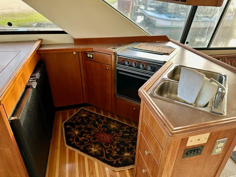 Slide: The Image of Interior of 1997 Bayliner 3988 Motoryacht kitchen with stove, sink, and wooden cabinetry. - 38