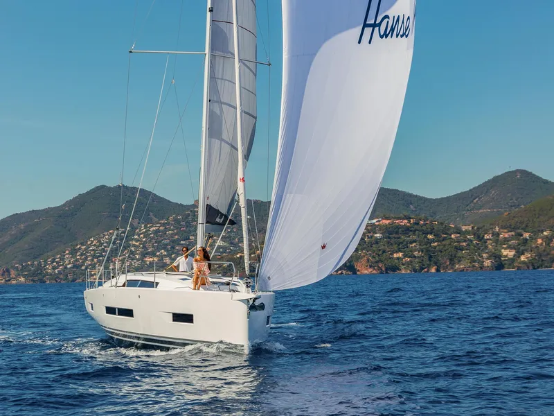 Slide: The Image of 2024 Hanse 410 sailboat cruising on open water with scenic mountain backdrop. - 8
