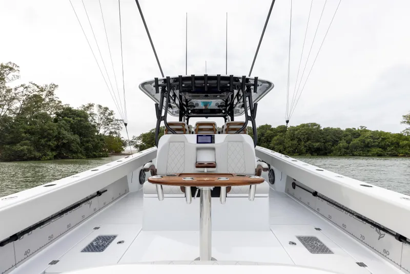 Slide: The Image of 2024 Freeman 42 LR boat interior with seating and table on a calm lake. - 24