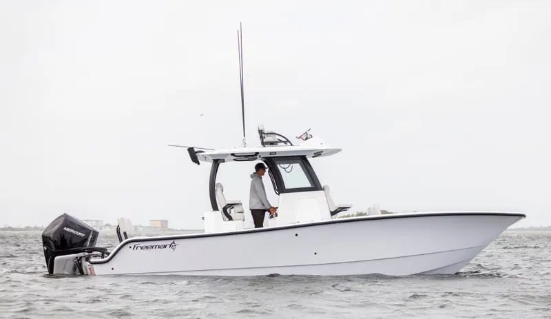 Slide: The Image of 2024 Freeman 28 boat on water with person standing at helm. - 2