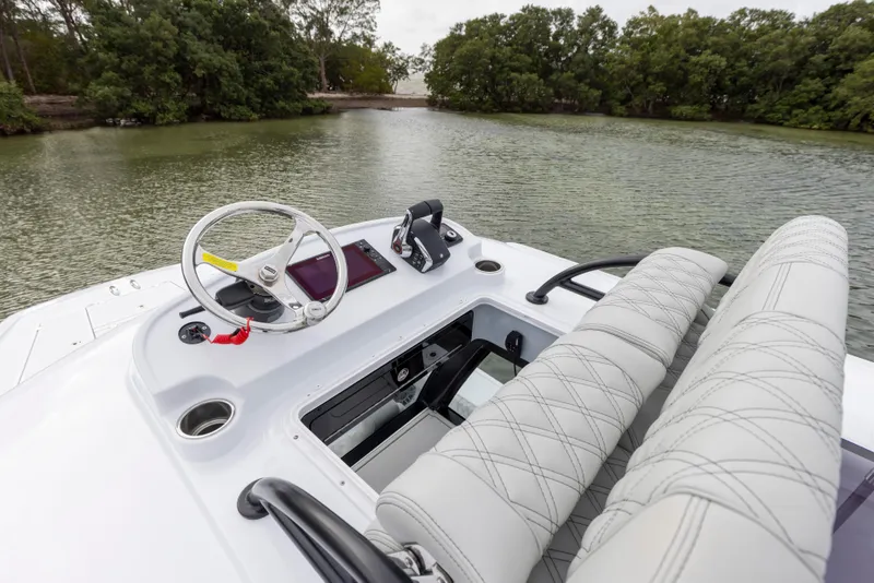 Slide: The Image of 2024 Freeman 28 boat cockpit with steering wheel and dual seats on a calm river. - 32