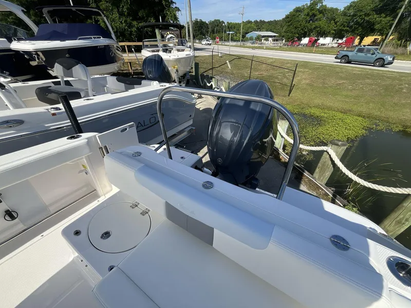 Slide: The Image of 2024 Robalo 222 Explore boat with outboard motor, docked near a grassy area. - 6