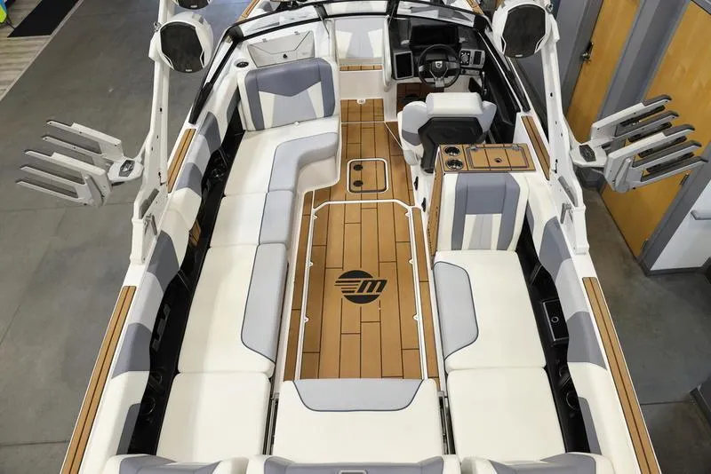 Slide: The Image of 2024 Malibu 24 MXZ boat interior with white and gray seating, wooden flooring, and modern dashboard. - 13