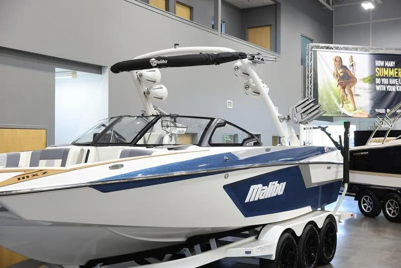 Slide: The Image of 2024 Malibu 24 MXZ boat displayed indoors on a trailer. - 19