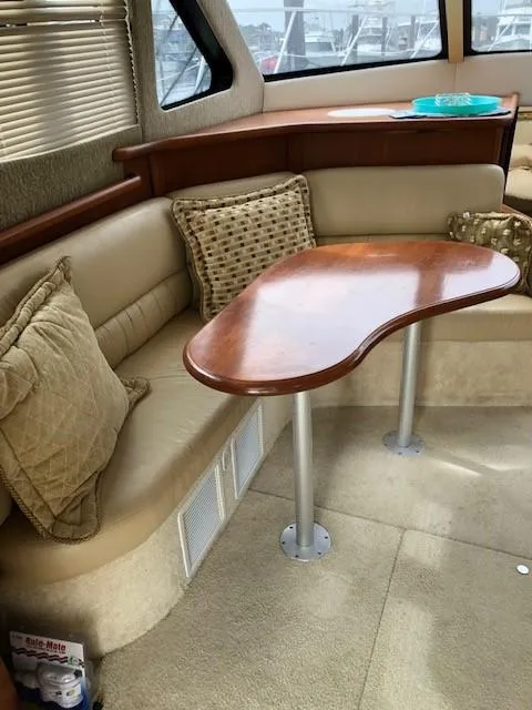 Slide: The Image of 2004 Silverton 34C yacht interior with beige seating and wooden table. - 24