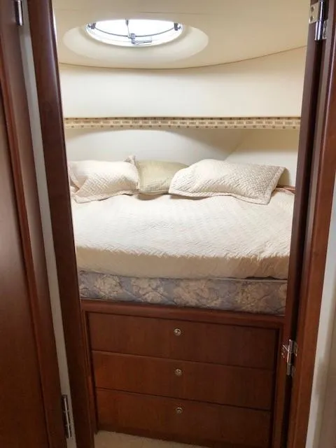 Slide: The Image of 2004 Silverton 34C cabin interior with bed, wooden drawers, and porthole. - 36