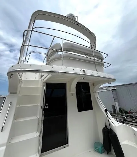 Slide: The Image of 2004 Silverton 34C yacht with upper deck and ladder, docked under cloudy sky. - 37