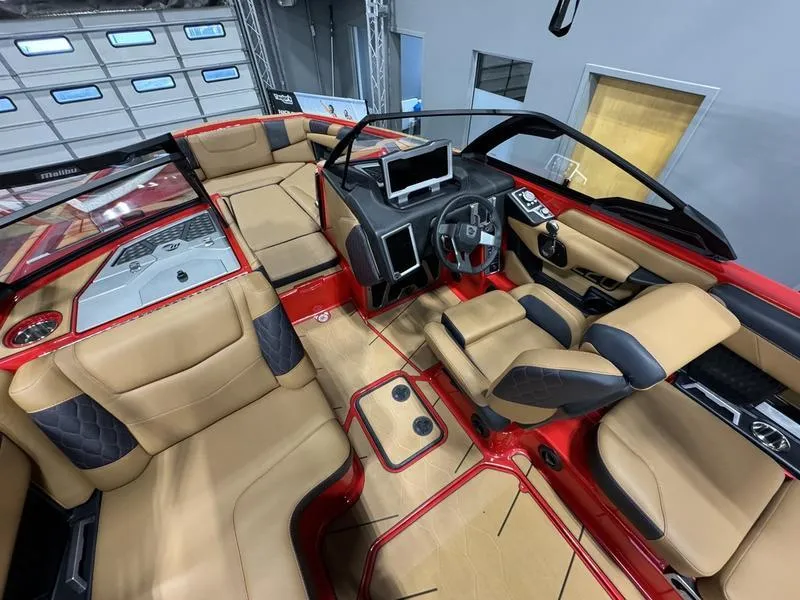 Slide: The Image of 2024 Malibu M220 boat interior with tan and black seating, modern dashboard, and red accents. - 7