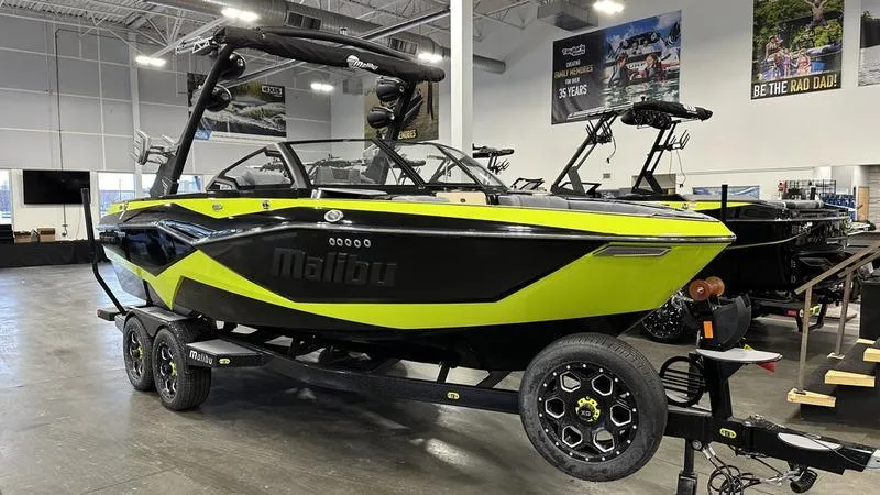 Slide: The Image of 2024 Malibu 22 LSV boat in showroom, black and green color scheme, on trailer. - 9
