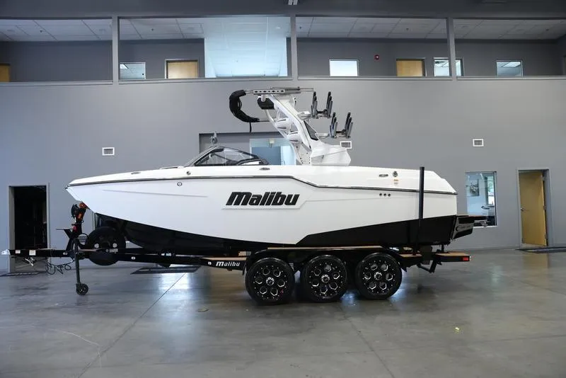 Slide: The Image of 2024 Malibu M220 boat on trailer in indoor showroom. - 1
