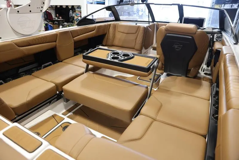 Slide: The Image of 2024 Malibu M220 boat interior with luxurious tan leather seating and a central table. - 19