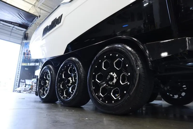 Slide: The Image of 2024 Malibu M220 boat trailer with black alloy wheels in a showroom. - 7