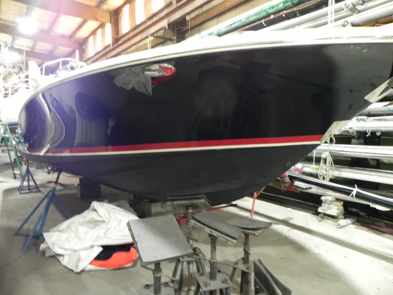 Slide: The Image of 2015 Chris-Craft 28 Heritage Corsair boat in storage, featuring sleek black hull with red stripe. - 9