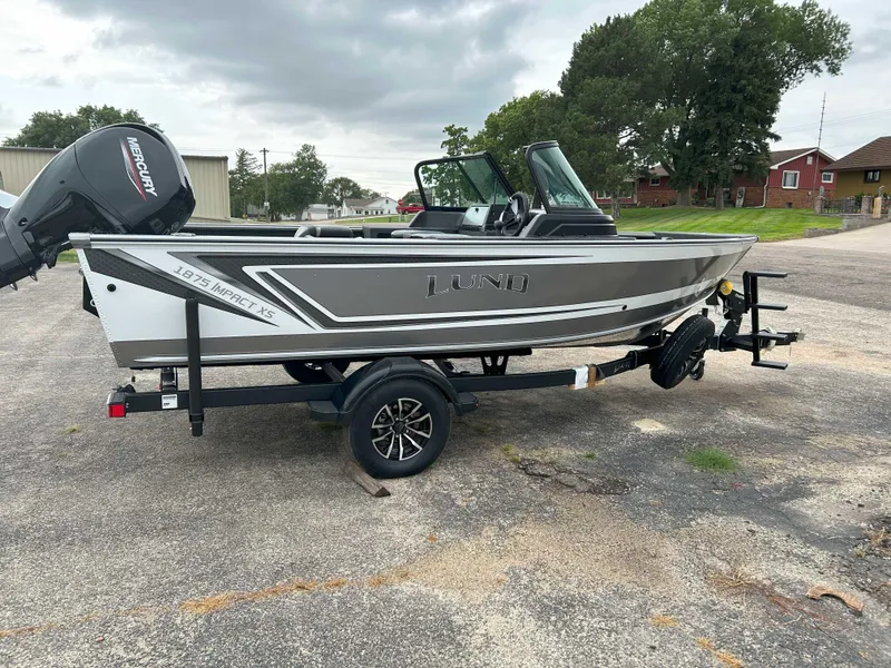 Slide: The Image of 2025 Lund 1875 Impact XS Fish boat on trailer, parked outdoors. - 8