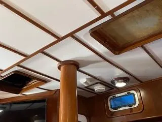 Slide: The Image of Interior ceiling of 1984 Tayana 55 sailboat with wooden beams and porthole. - 12