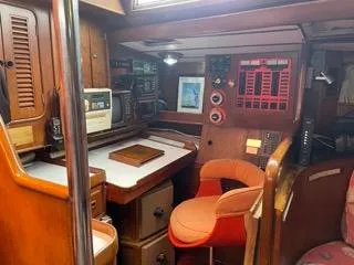 Slide: The Image of Navigation station of a 1984 Tayana 55 sailboat with wooden cabinetry and red chair. - 21
