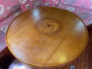 Slide: The Image of Round wooden table on a 1984 Tayana 55 yacht with pink patterned seating. - 26