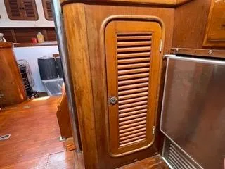 Slide: The Image of Wooden interior of 1984 Tayana 55 sailboat with louvered cabinet door and stainless steel fridge. - 28