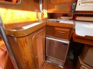 Slide: The Image of 1984 Tayana 55 yacht galley with wooden cabinetry, sink, and mini fridge. - 30