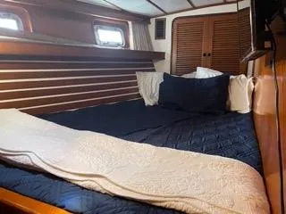 Slide: The Image of Cozy bedroom in a 1984 Tayana 55 sailboat with wooden accents and porthole windows. - 33