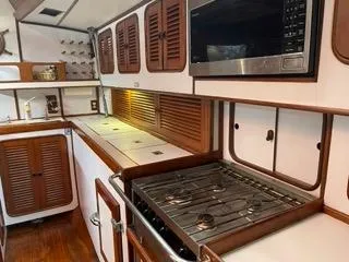 Slide: The Image of Galley kitchen in 1984 Tayana 55 sailboat with stove, microwave, and wooden cabinets. - 8