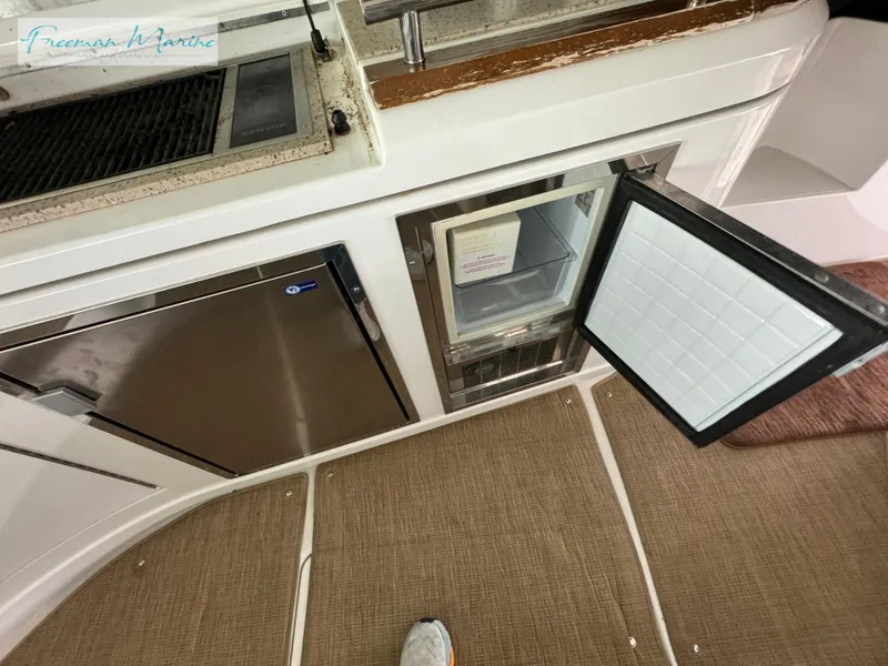 Slide: The Image of 2014 Cruisers Yachts 540 Sports Coupe kitchen area with open mini fridge and stainless steel appliances. - 45