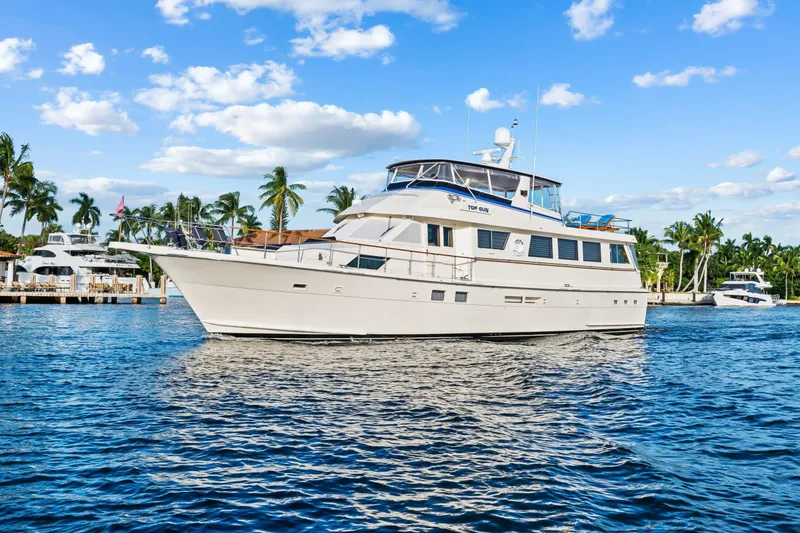 Slide: The Image of 1989 Hatteras 70 Motor Yacht cruising on a sunny day with palm trees in the background. - 0