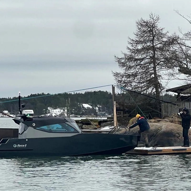 Slide: The Image of 2024 G-Force 8 boat docked at a snowy lakeside with people on the pier. - 2