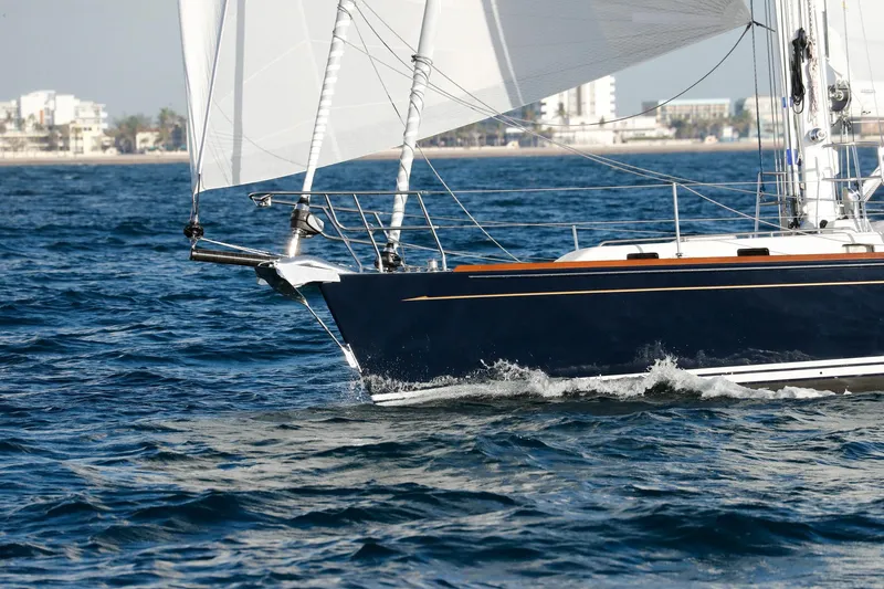 Slide: The Image of Sailing yacht Outbound 46, 2025 model, cruising on open water near a coastal city. - 7