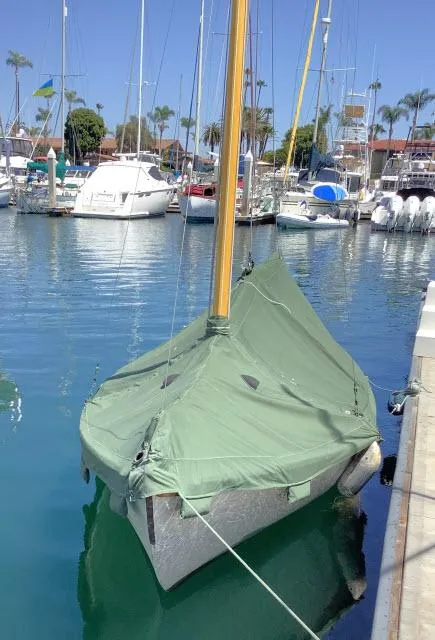 Slide: The Image of Custom Haven 12.5 sailboat, 1994 model, docked with a green cover in a marina. - 4