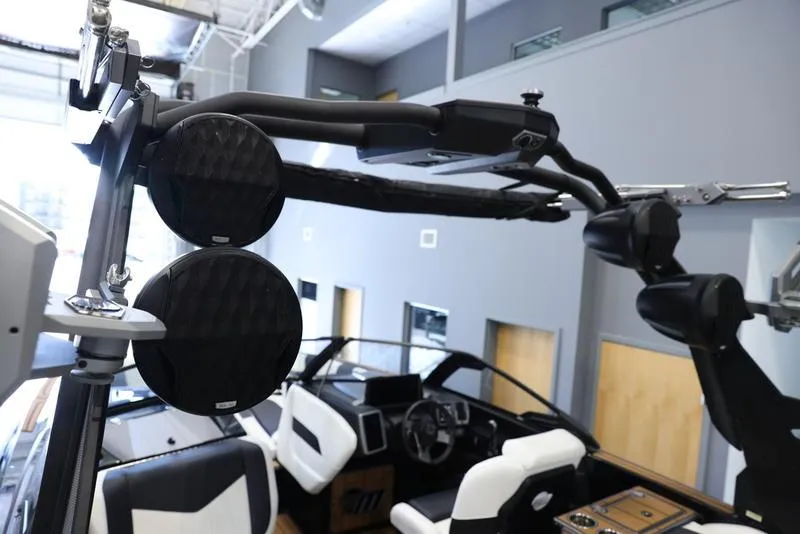 Slide: The Image of 2024 Malibu 24 MXZ boat interior with black and white seating and advanced audio system. - 11