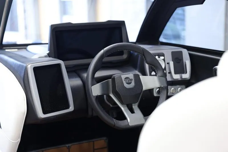 Slide: The Image of 2024 Malibu 24 MXZ boat dashboard with modern steering wheel and digital displays. - 12
