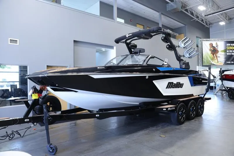 Slide: The Image of 2024 Malibu 24 MXZ boat in showroom, black and white exterior, on trailer. - 3