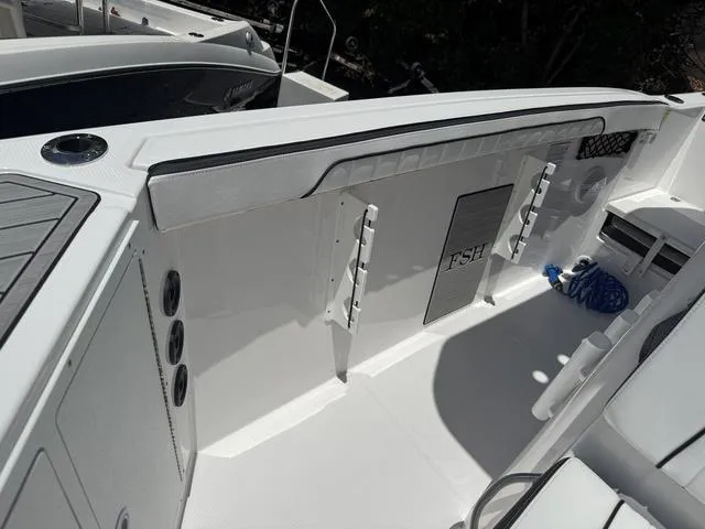Slide: The Image of 2024 Yamaha Boats 222 FSH Sport interior, featuring sleek white design and fishing rod holders. - 36