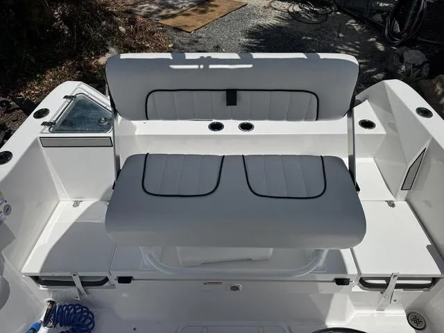 Slide: The Image of 2024 Yamaha Boats 222 FSH Sport interior seating with white cushioned bench and storage compartments. - 37