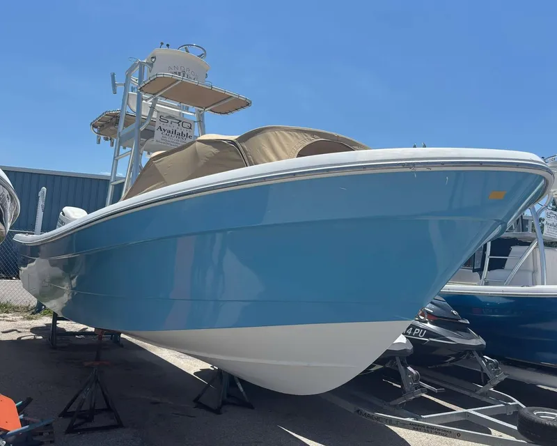 The Image of 2009 Andros Tarpon 26 boat with blue hull, docked on land under clear sky. - 0