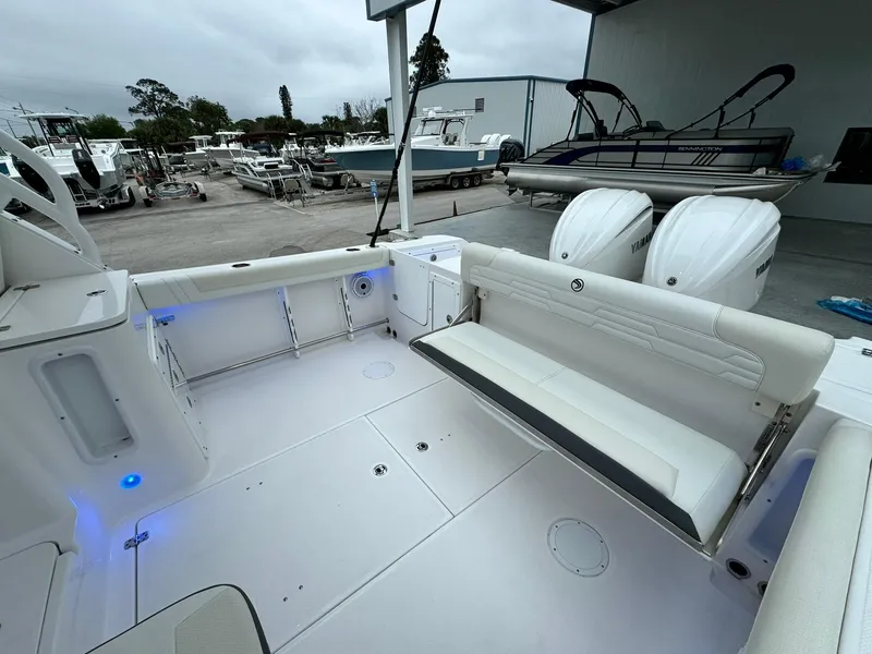 Slide: The Image of 2024 Edgewater 280cx boat interior with seating and dual outboard motors. - 13