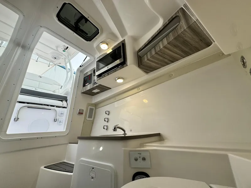 Slide: The Image of 2024 Edgewater 280cx boat interior with kitchenette and seating area. - 24
