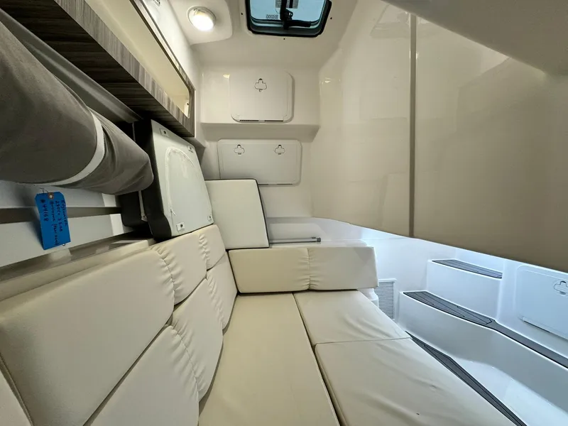 Slide: The Image of 2024 Edgewater 280cx cabin interior with white cushioned seating and storage compartments. - 26