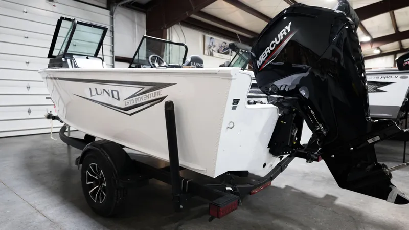 The Image of 2024 Lund 1675 Adventure Sport boat with Mercury outboard motor in a showroom. - 1