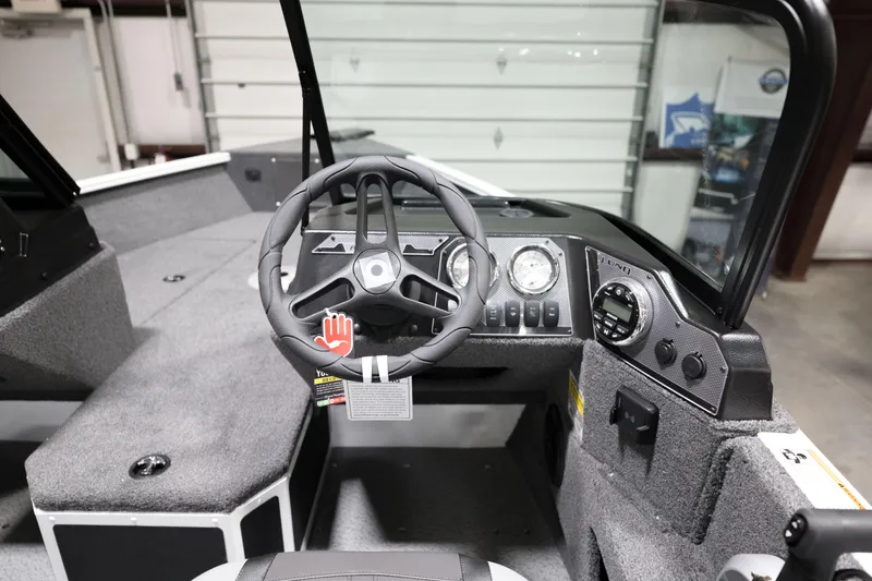 Slide: The Image of 2024 Lund 1675 Adventure Sport boat cockpit with steering wheel and dashboard controls. - 16
