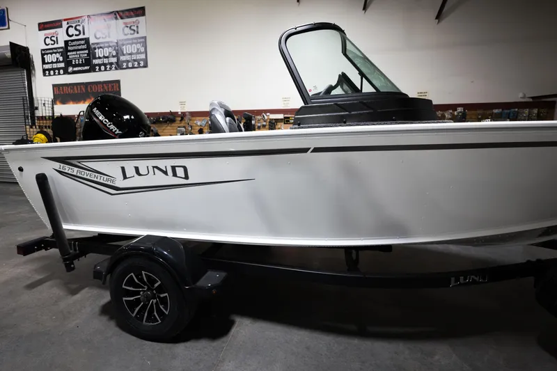 Slide: The Image of 2024 Lund 1675 Adventure Sport boat on display in a showroom. - 6