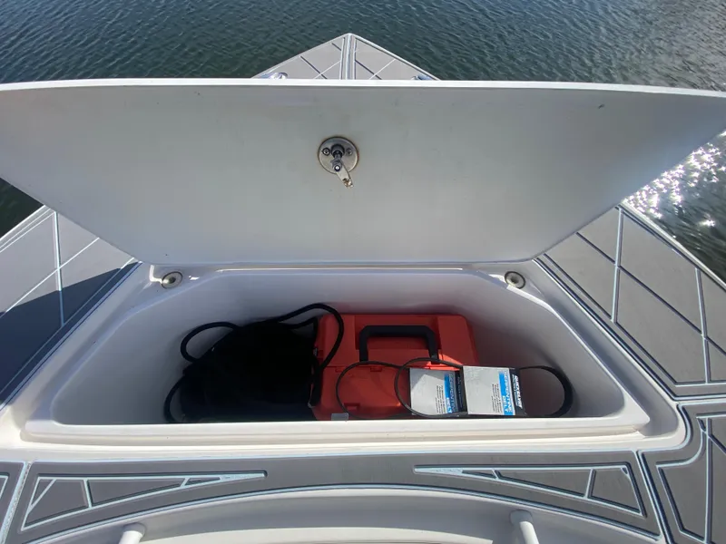 Slide: The Image of Open storage compartment on 2022 Fountain 34 Tournament Edition boat, containing safety equipment. - 27