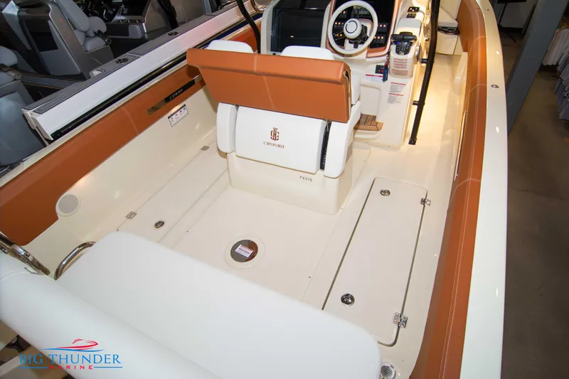 Slide: The Image of 2024 Capoforte FX270 boat interior with tan and white seating, steering console, and storage compartments. - 21