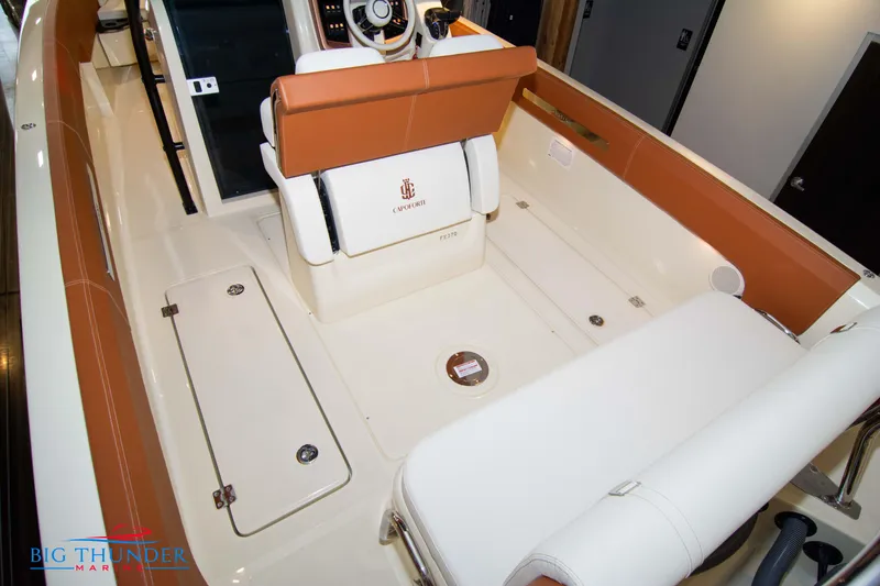 Slide: The Image of 2024 Capoforte FX270 boat interior with tan and white seating, storage compartments. - 22